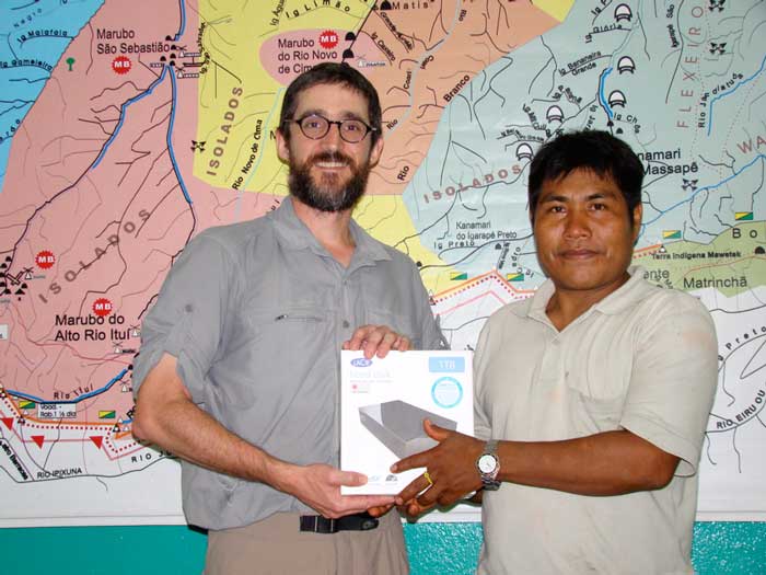 Javier Ruedas hands a hard drive to Alfredo Barbosa, a Marubo man.